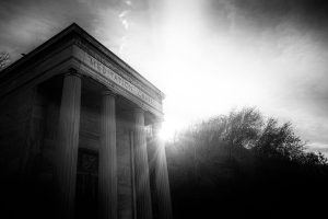 Striking black and white image of a classical meditation chapel at sunrise with dramatic lighting.